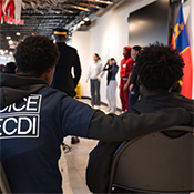 Un élève portant un t‑shirt «&nbsp;Junior DICE ECDI&nbsp;» est assis, le bras autour d'un autre élève, pendant une présentation de la GRC au Collège canadien de police.