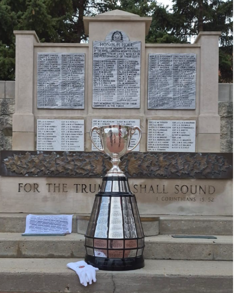 Un trophée en argent et une petite couverture blanche sont posés devant un monument de pierre et de marbre portant le nom des policiers de la GRC décédés dans l’exercice de leurs fonctions.