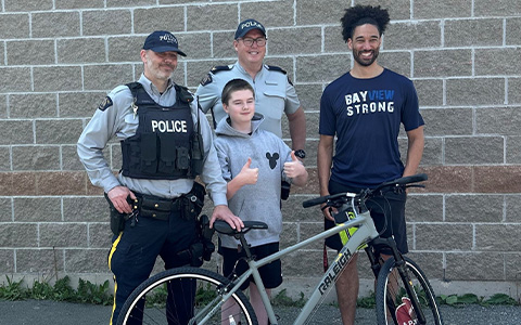 Quatre personnes, dont un enfant et deux policiers, se tiennent derrière un vélo.