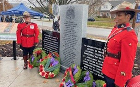 Deux agents de la GRC en tunique rouge se tiennent devant un monument.