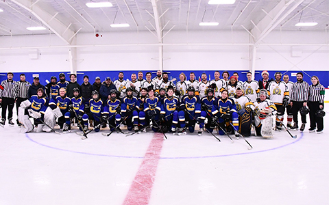 Deux équipes de hockey et des arbitres posent pour une photo sur la glace.