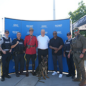 Sept membres de la GRC en compagnie du commissaire de la LCF Randy Ambrosie devant une bannière bleue portant la mention RCMP-GRC.
