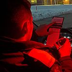 Un cadet écrit dans son cahier alors qu'il est assis dans son véhicule la nuit.