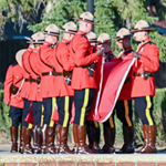 Un groupe de cadets en tunique rouge plient ensemble le drapeau du Canada.