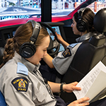 Deux cadettes utilisent un simulateur de conduite. L'une lit les directives pendant que l'autre conduit.