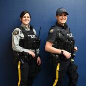 Deux membres de la GRC en uniforme : l’un porte la chemise grise à manches longues, l’autre la nouvelle chemise d’uniforme bleu marine à manches courtes.