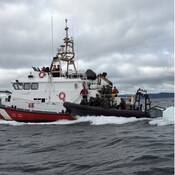 Un grand navire de la Garde côtière canadienne et un zodiac de la GRC naviguent côte à côte sur l’eau.