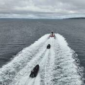 Un grand navire de la Garde côtière canadienne en pleine mer, suivi de près dans son sillage par deux zodiacs de la GRC.