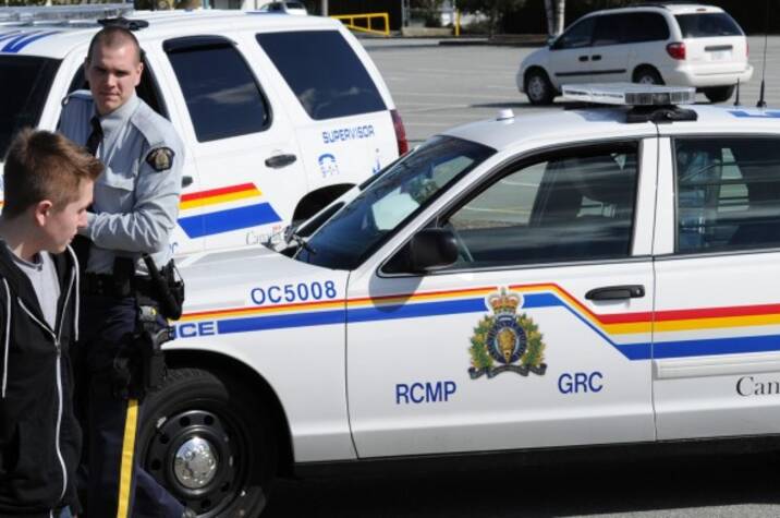 RCMP approach a young man in a parking lot.