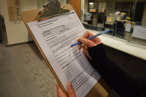 une personne sur le point de remplir le formulaire Vérification de l’information policière sur une planchette à pinces.